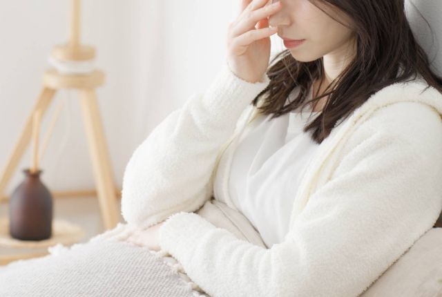 ベッドで辛そうにしている女性